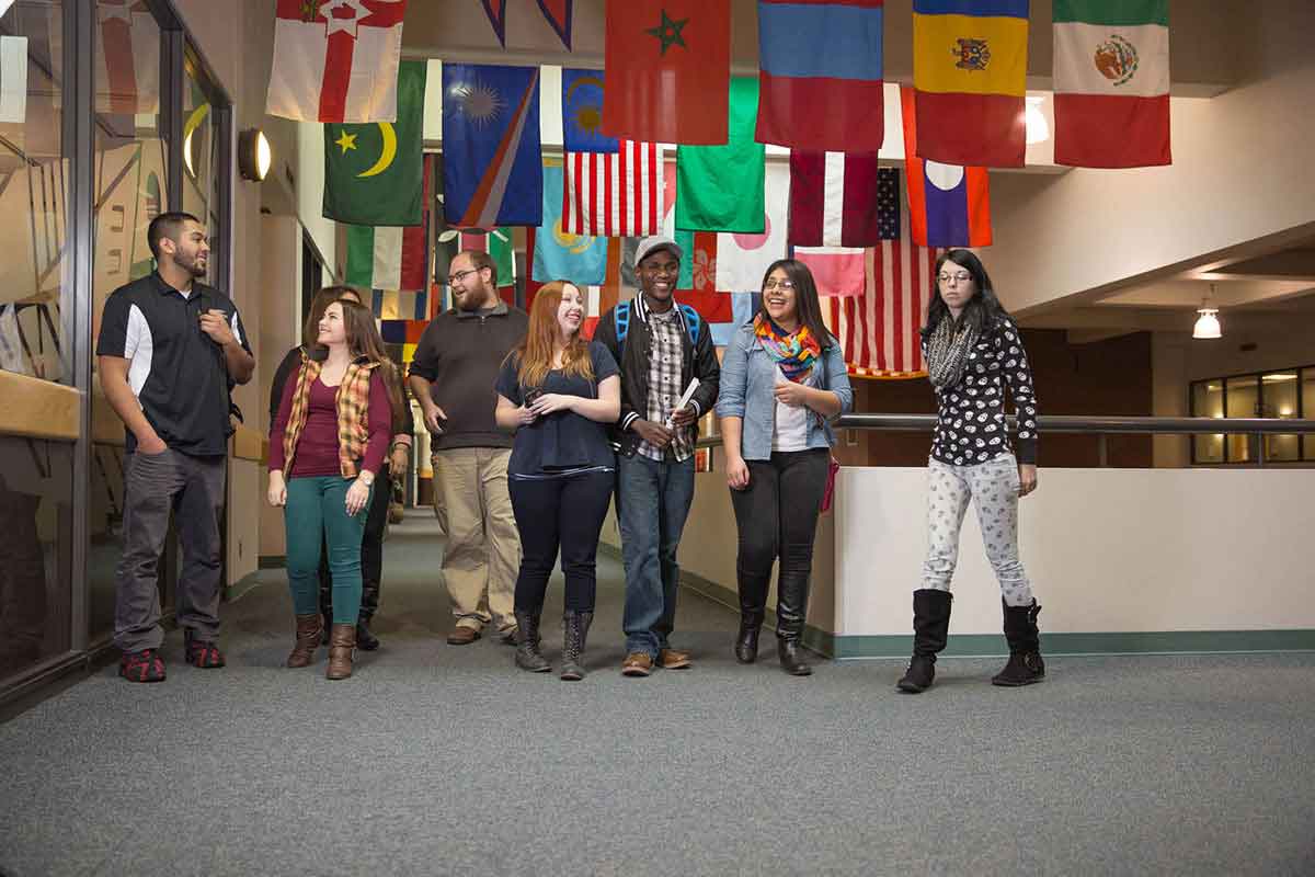 A group of students talking beneath rows of flags from different countries